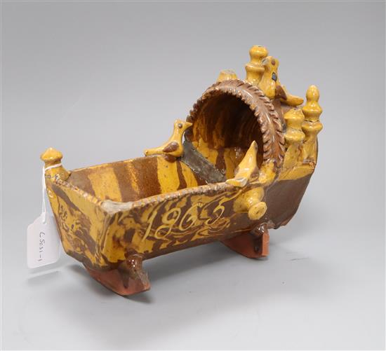 A 19th century documentary slipware model of a cradle, initialled SP and dated 1865, length 25cm (a.f.)
